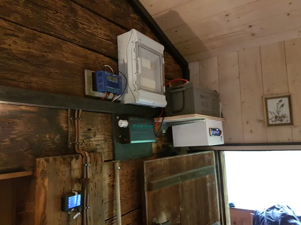 Solartechnik an der Holzwand: Laderegler, Batterie und Sicherungskasten