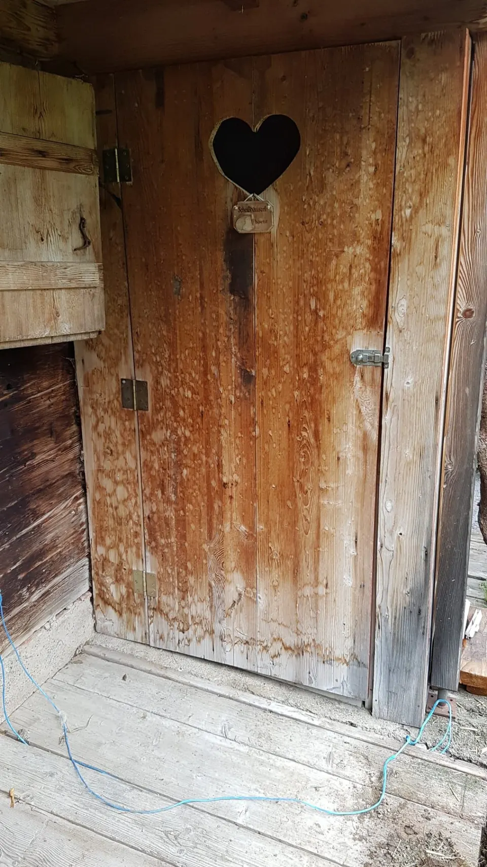 Holztür des Aussen-WCs mit herzförmigem Ausschnitt